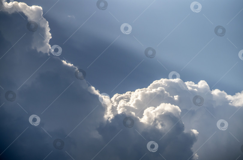 Скачать Солнечный луч подобен прожектору, светящему из-за огромных кучевых облаков фотосток Ozero