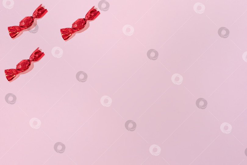 Скачать Креативный праздничный узор из красных конфет на розовом фоне копирует пространство для текста фотосток Ozero
