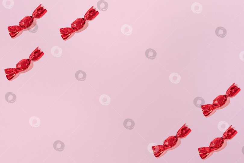 Скачать Креативный праздничный узор из красных конфет на розовом фоне копирует пространство для текста фотосток Ozero