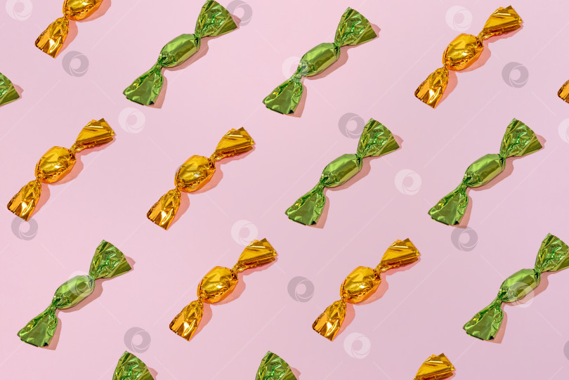 Скачать Креативный праздничный узор из разноцветных шоколадных конфет на розовом фоне минимализм фотосток Ozero