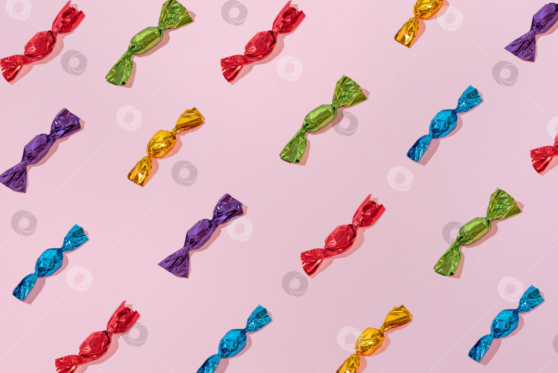Скачать Креативный праздничный узор из разноцветных шоколадных конфет на розовом фоне минимализм фотосток Ozero
