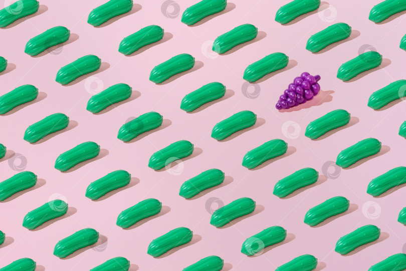 Скачать Креативный узор из огурцов и винограда на ровном пастельно-розовом фоне, минимализм фотосток Ozero
