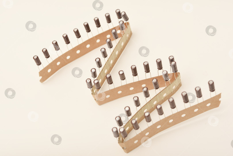 Скачать Старые конденсаторы в бумажной обертке. Алюминиевые конденсаторы на белом фоне. Электронные компоненты находятся в оригинальной упаковке. фотосток Ozero