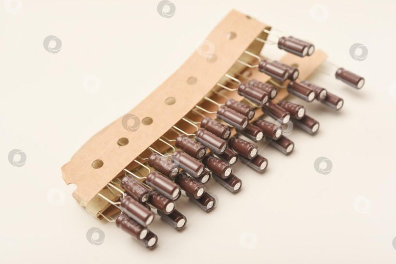 Скачать Старые конденсаторы в бумажной обертке. Алюминиевые конденсаторы на белом фоне. Электронные компоненты находятся в оригинальной упаковке. фотосток Ozero