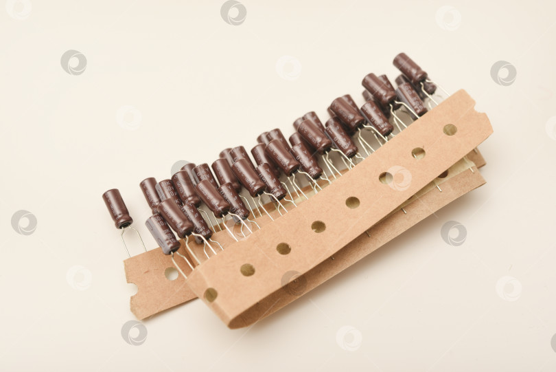 Скачать Старые конденсаторы в бумажной обертке. Алюминиевые конденсаторы на белом фоне. Электронные компоненты находятся в оригинальной упаковке. фотосток Ozero