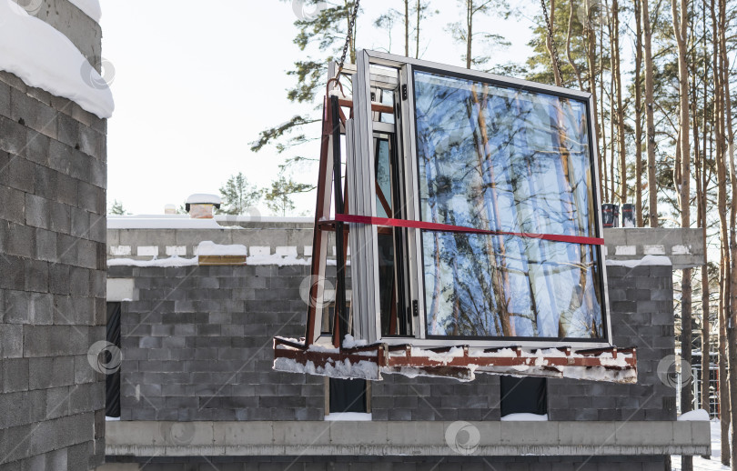 Скачать Кран поднимает пластиковые окна на строительной площадке фотосток Ozero