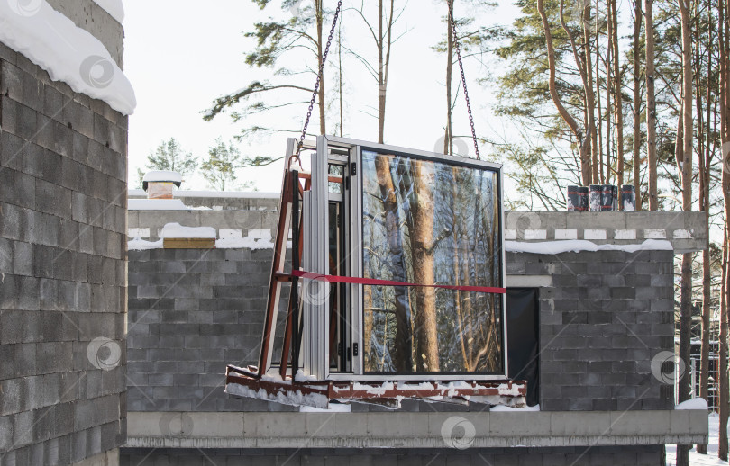 Скачать Кран поднимает пластиковые окна на строительной площадке фотосток Ozero