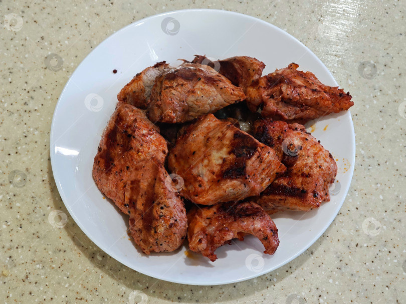 Скачать На белой тарелке кусочки мяса, приготовленные на электрическом гриле в помещении на кухне. На белой тарелке лежит мясо, приготовленное на электрическом гриле в закрытом помещении кухни. фотосток Ozero