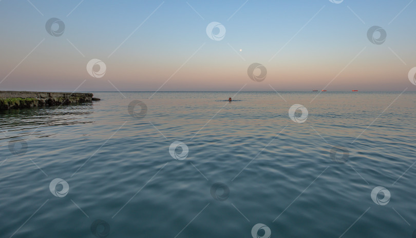 Скачать спокойное море с лёгкой рябью. Вдали виден человек, плавающий в воде. фотосток Ozero