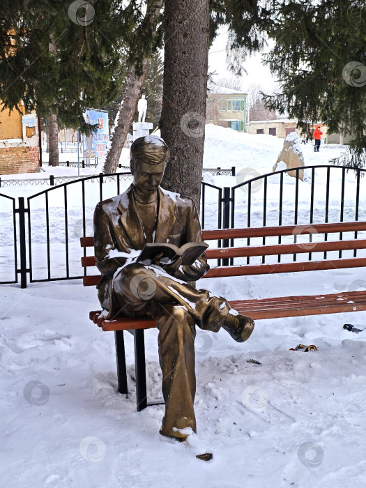 Скачать Скульптура, мужчина читает книгу в парке на лавочке зимой. Село в Алтайском крае. Скульптура, изображающая мужчину, читающего книгу в парке на скамейке зимой. фотосток Ozero
