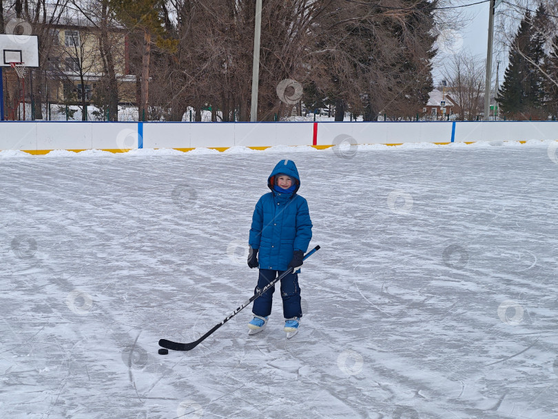 Скачать Мальчик с клюшкой на льду хоккейной коробки. Мальчик с клюшкой на льду хоккейной коробки. фотосток Ozero