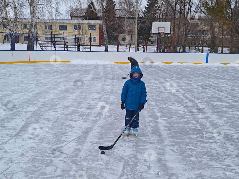 Скачать Мальчик с клюшкой на льду хоккейной коробки. Мальчик с клюшкой на льду хоккейной коробки. фотосток Ozero