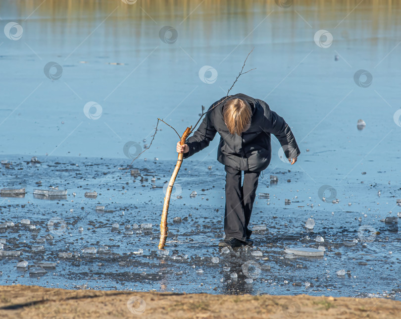 Скачать Россия,Сибирь 08 августа 2025 год.Мальчик на льду пытается пробить палкой лед фотосток Ozero