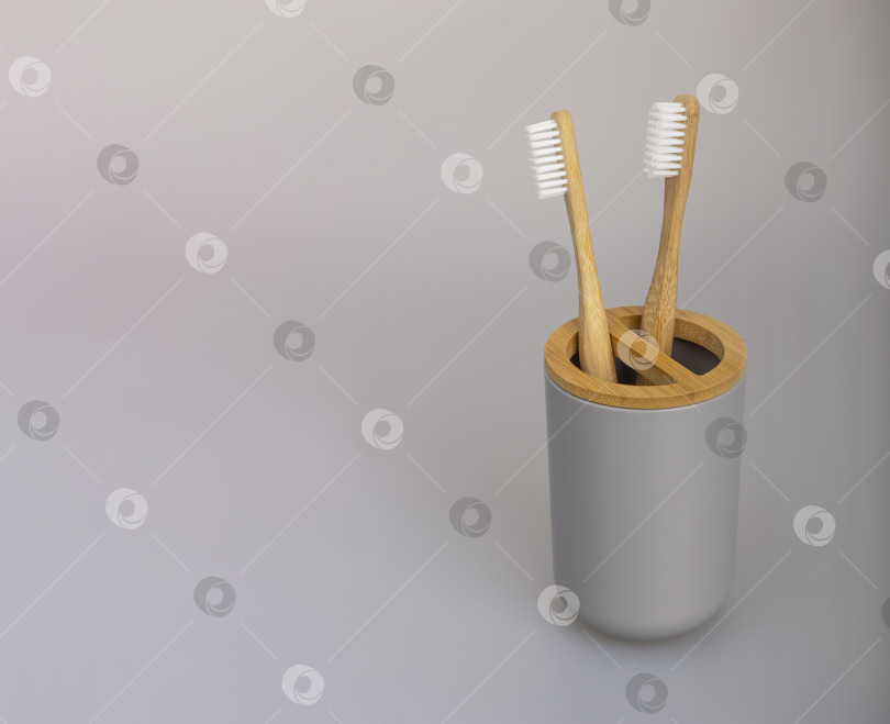 Скачать Две бамбуковые зубные щетки в пластиковом держателе на сером фоне. Экологичная концепция без отходов. Выделите место для текста фотосток Ozero