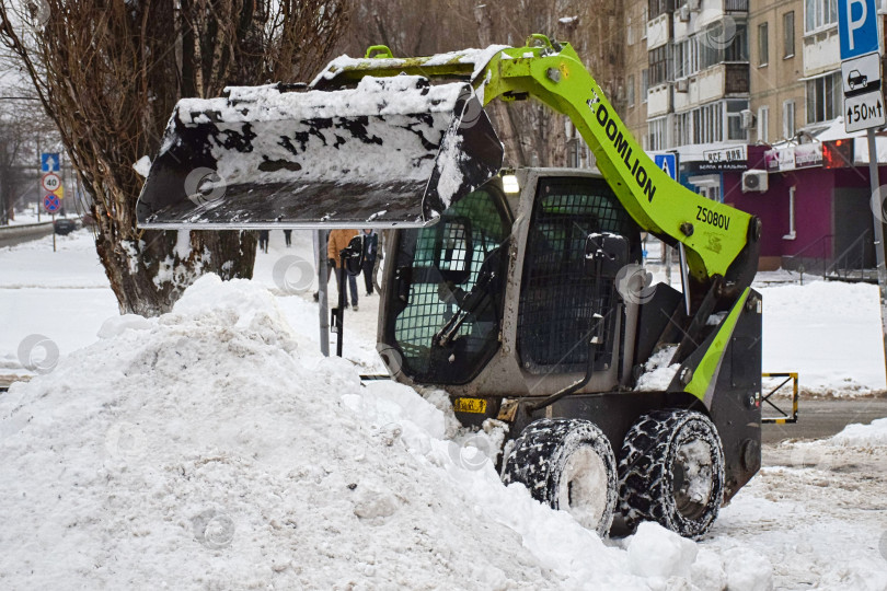 Скачать Уборка снега погрузчиком после снегопада в городе. фотосток Ozero