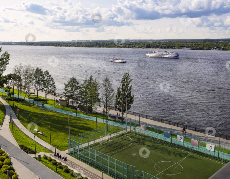 Скачать Городская набережная города Перми. Футбольное поле и прогулочная зона на переднем плане. По реке движутся теплоходы.  Россия. Перманент. Река Кама. 2024.08.20 фотосток Ozero