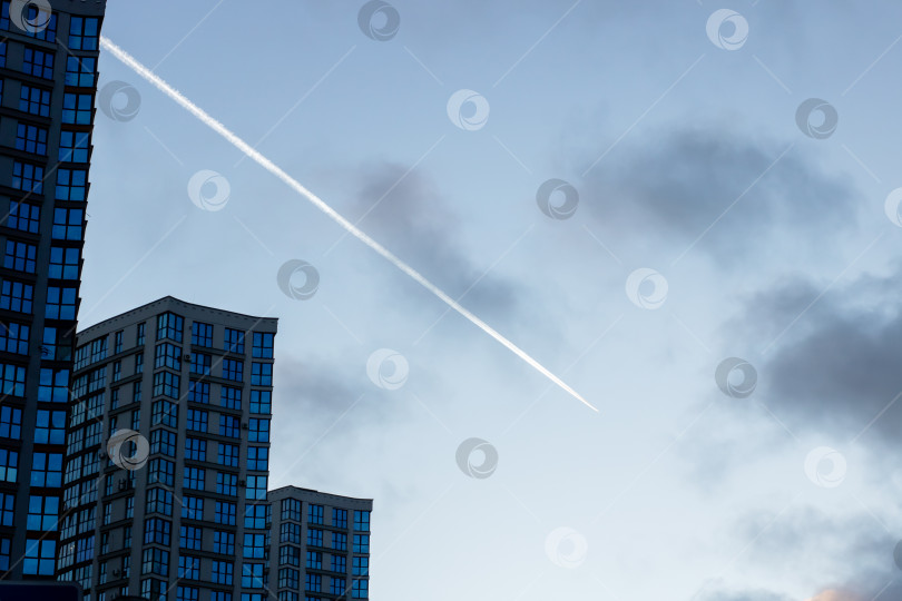 Скачать Городской пейзаж со следом летящего реактивного самолета, городской пейзаж в сумерках, на котором видны полосы и силуэты самолетов фотосток Ozero