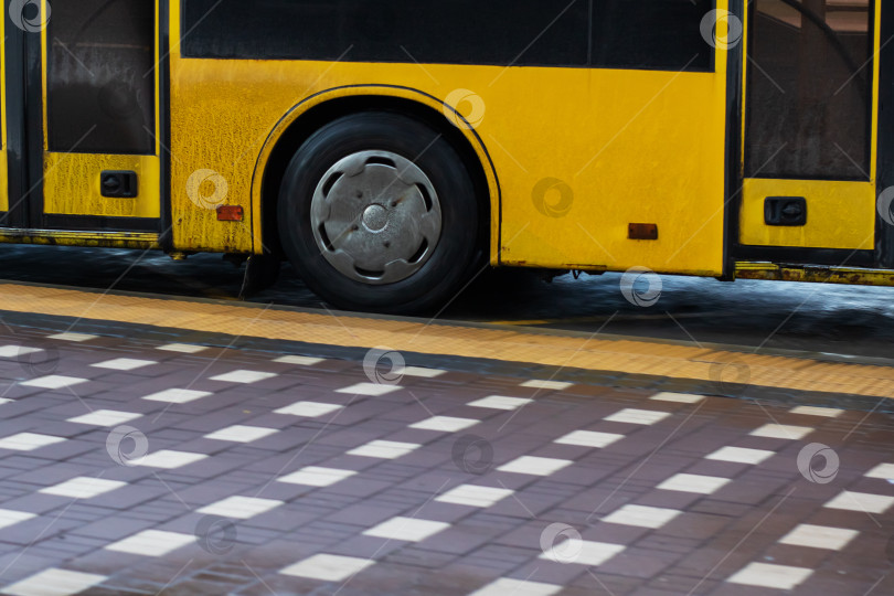 Скачать Крупный план желтого колеса автобуса и тротуара, детальный вид колеса автобуса на мокром городском асфальте фотосток Ozero