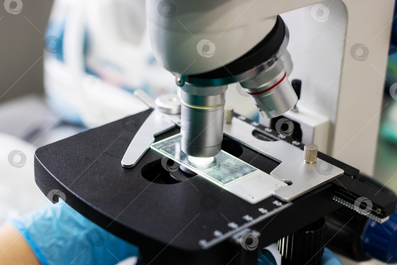 Скачать Ученый-клиницист, анализирующий особенности клеток с помощью микроскопа на подготовленном предметном стекле фотосток Ozero