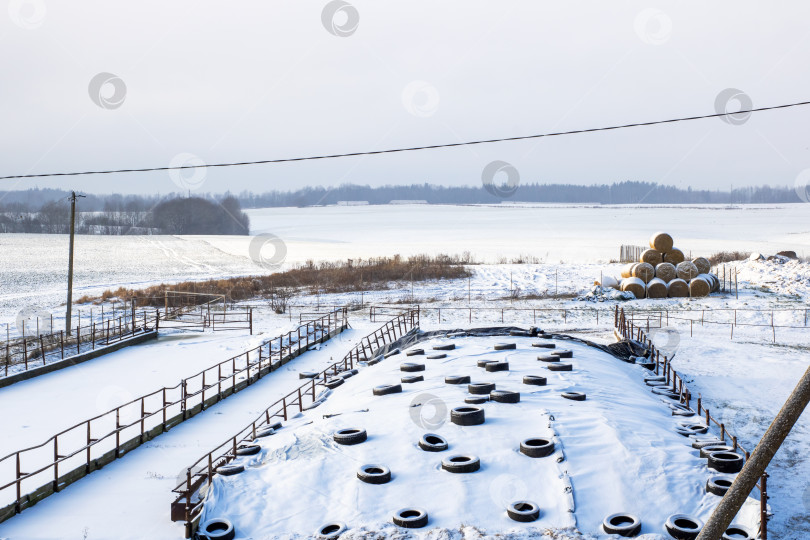 Скачать Замерзшая набережная с деревенскими элементами, заснеженный промышленный пейзаж с сельским спокойствием фотосток Ozero