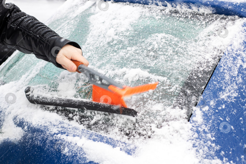 Скачать Человек, быстро удаляющий лед с автомобиля, - обычная процедура морозным утром для безопасной очистки обледеневшего лобового стекла фотосток Ozero