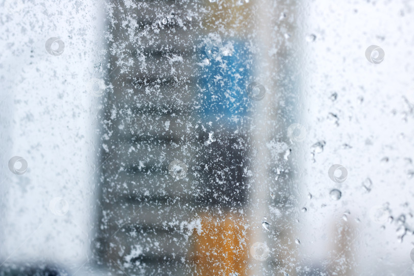 Скачать Перспектива офисного работника, наблюдающего за заснеженным городским пейзажем через заледеневшее окно фотосток Ozero