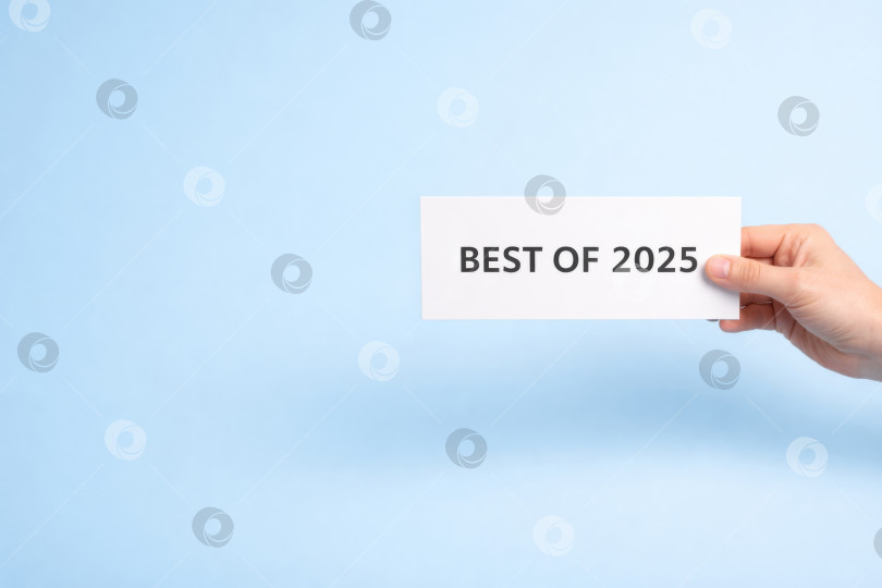 Скачать Концепт Best of 2025 с картой, которую вы держите в руке, на светло-голубом фоне фотосток Ozero