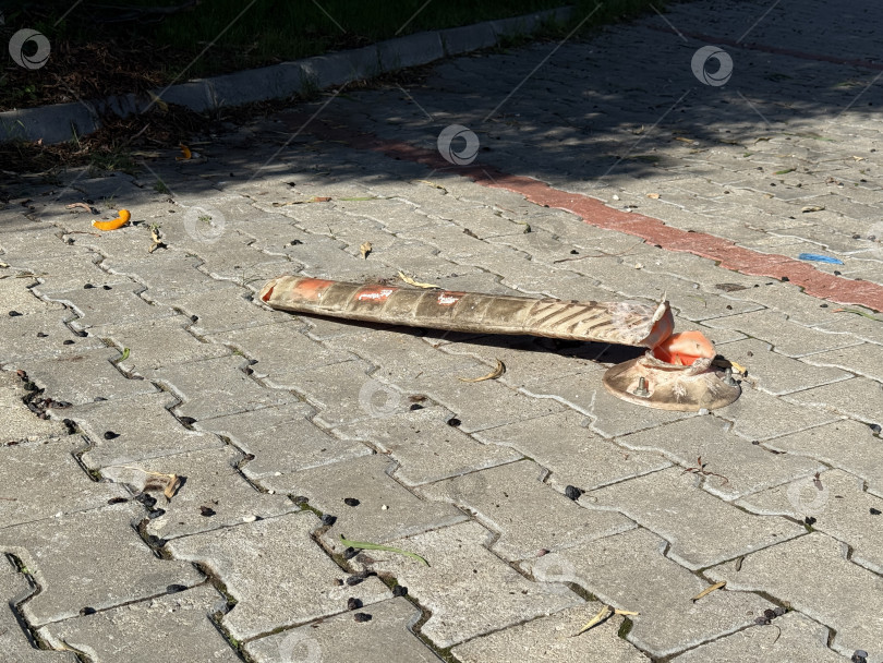 Скачать Упавший дорожный конус на асфальтированной поверхности, отбрасывающий тень, олицетворяет городской упадок и запущенность фотосток Ozero