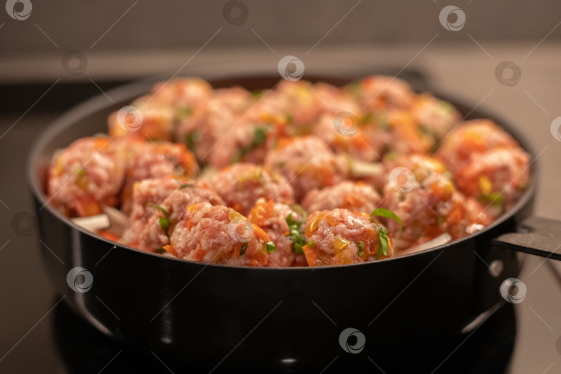 Скачать Мясные фрикадельки аппетитно готовятся в сковороде на овощной подушке из репчатого лука, помидор и моркови фотосток Ozero