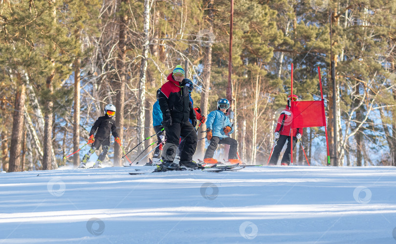 Скачать Россия, Красноярск 25 февраля 2025г. Спортивный тренер и инструктор по лыжному спорту работает со своими учениками на заснеженном горнолыжном склоне. фотосток Ozero