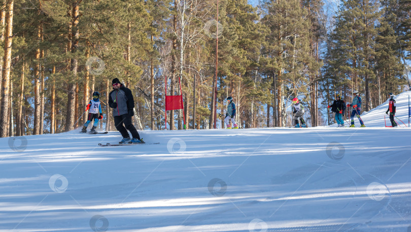 Скачать Россия, Красноярск 25 февраля 2025г. Спортивный тренер и инструктор по лыжному спорту работает со своими учениками на заснеженном горнолыжном склоне. фотосток Ozero