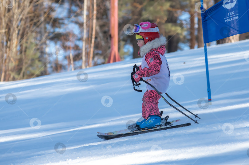 Скачать Россия, Красноярск 25 февраля 2025г. Маленькая девочка лыжница, спускается на лыжах по снежному склону. фотосток Ozero