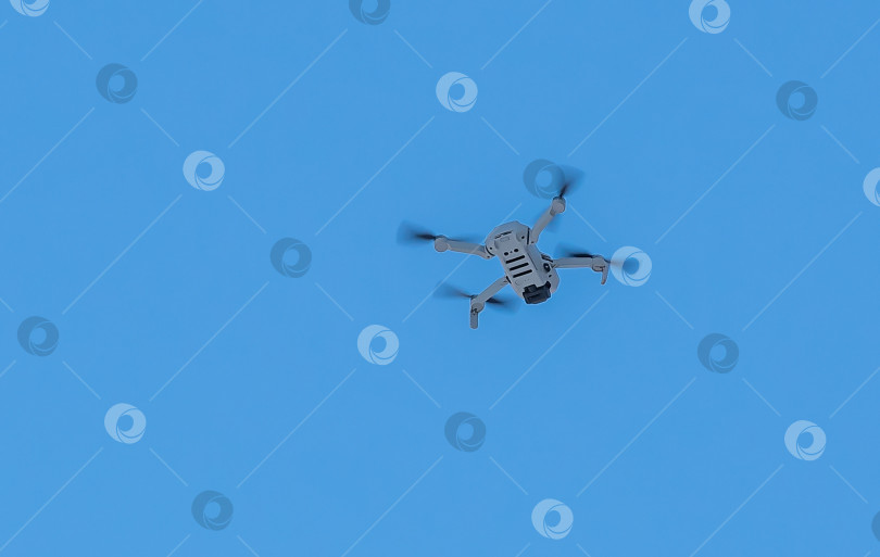 Скачать Россия,Сибирь 27 Мая 2025 год. Серый дрон с четырьмя винтами на фоне голубого неба. Дрон находится в полёте. фотосток Ozero