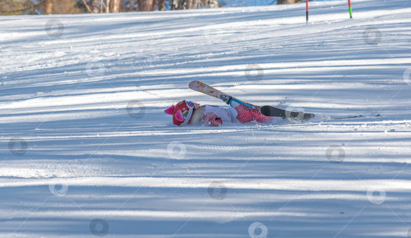 Скачать Россия, Красноярск 25 февраля 2025г.  Девочка лыжница, упала на лыжах, катаясь  по снежному склону. фотосток Ozero