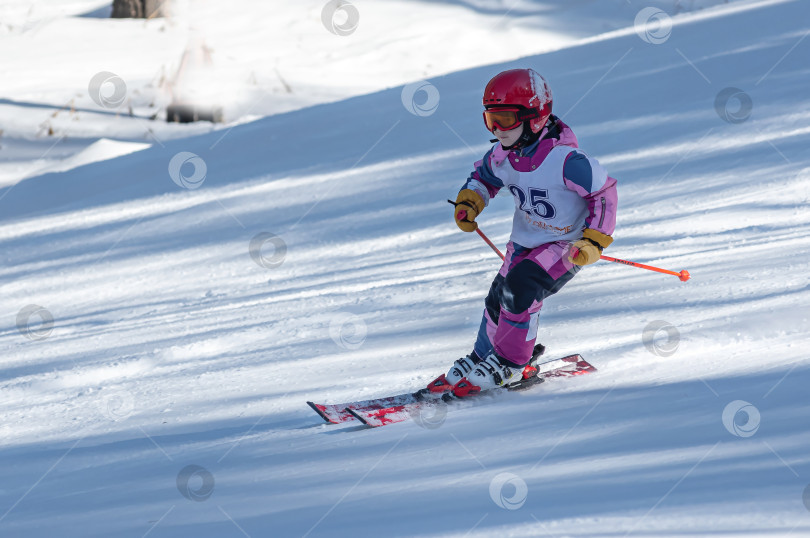 Скачать Россия, Красноярск 25 февраля 2025г. Девочка лыжница, спускается на лыжах по снежному склону. фотосток Ozero