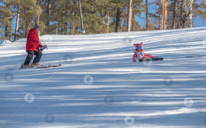 Скачать Россия, Красноярск 25 февраля 2025г.  Девочка лыжница, упала на лыжах, катаясь  по снежному склону. фотосток Ozero