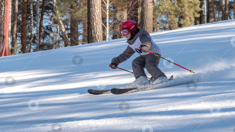 Скачать Россия, Красноярск 25 февраля 2025г. Мальчик лыжник, спускается на лыжах по снежному склону. фотосток Ozero