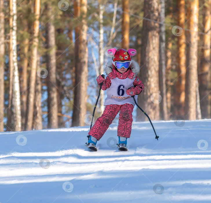 Скачать Россия, Красноярск 25 февраля 2025г. Маленькая девочка лыжница, спускается на лыжах по снежному склону. фотосток Ozero