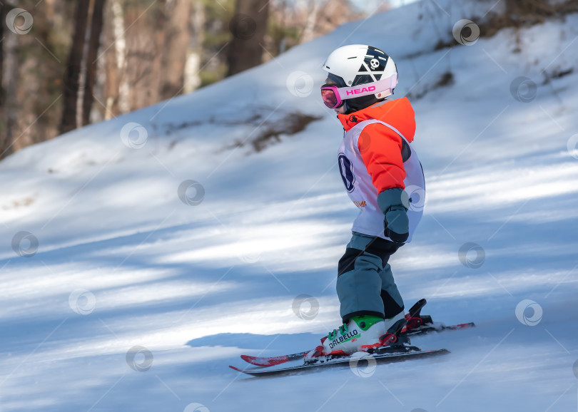 Скачать Россия, Красноярск 25 февраля 2025г. Мальчик лыжник, спускается на лыжах по снежному склону. фотосток Ozero
