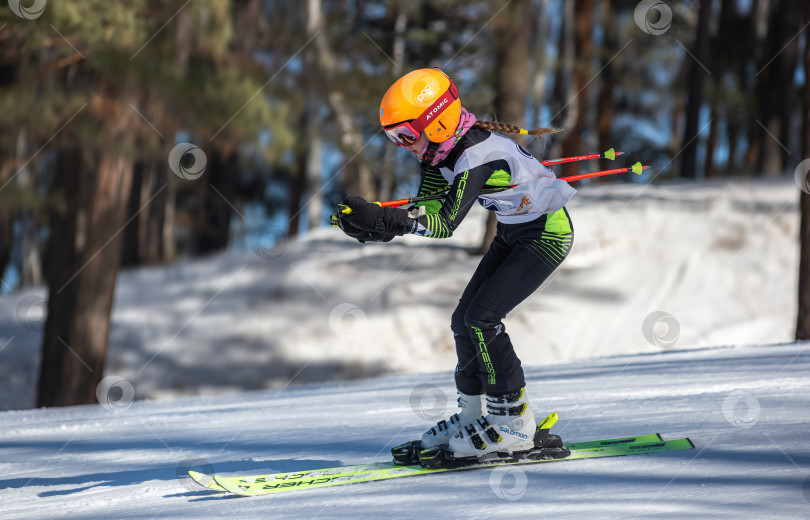 Скачать Россия, Красноярск 25 февраля 2025г. Девочка лыжница, спускается на лыжах по снежному склону. фотосток Ozero