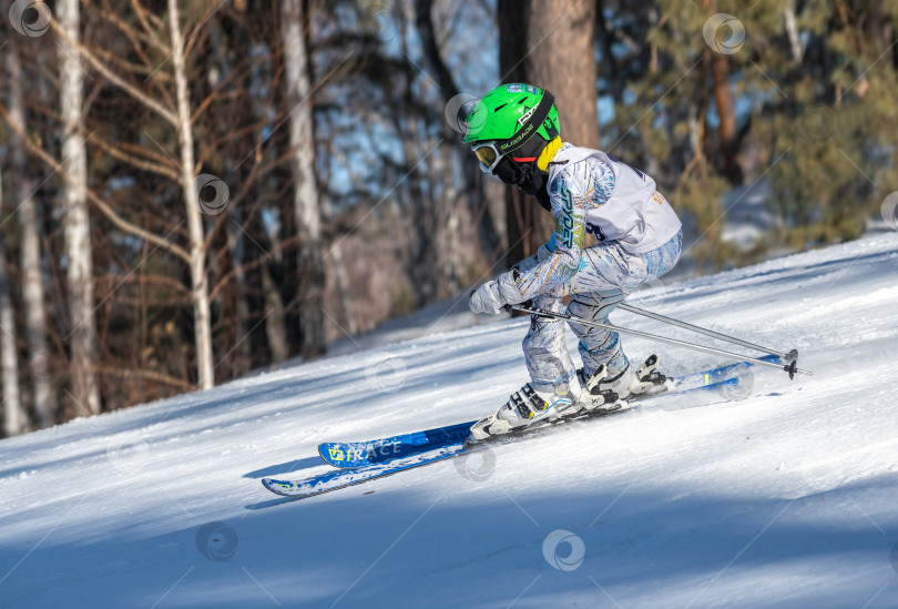 Скачать Россия, Красноярск 25 февраля 2025г. Мальчик лыжник, спускается на лыжах по снежному склону. фотосток Ozero