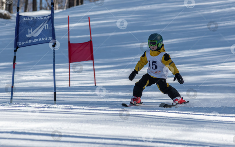 Скачать Россия, Красноярск 25 февраля 2025г. Мальчик лыжник, спускается на лыжах по снежному склону. фотосток Ozero