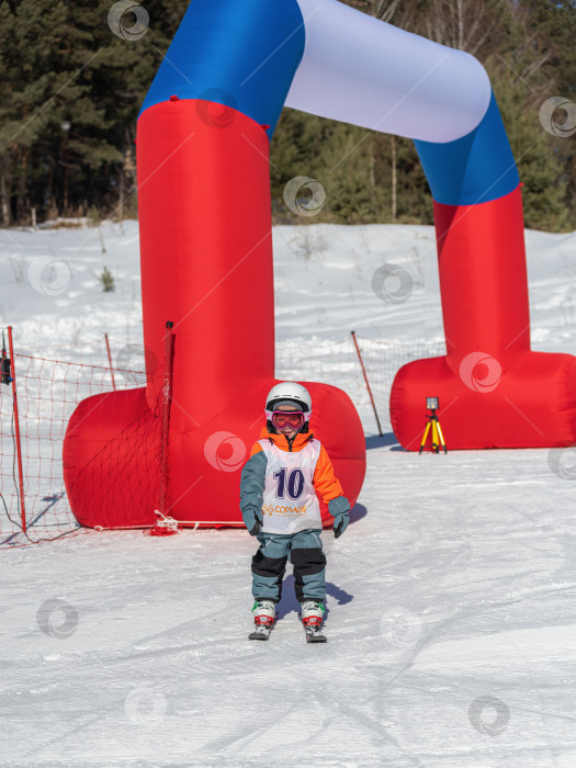 Скачать Россия, Красноярск 25 февраля 2025г.  ребёнок в лыжной экипировке стоит на снегу. На нём шлем фотосток Ozero