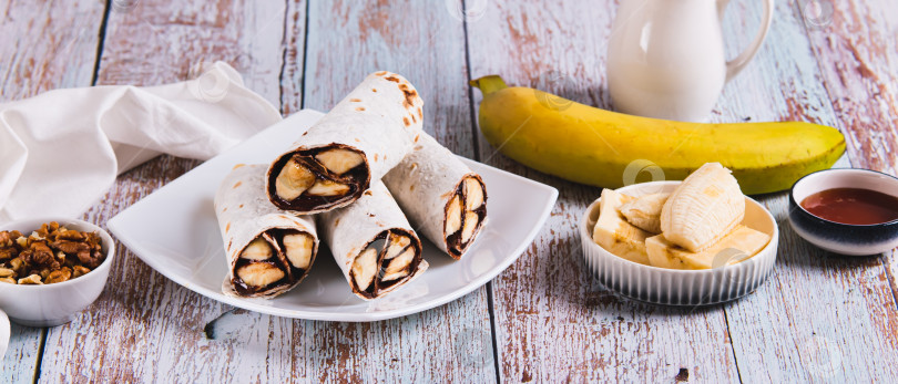 Скачать Сладкие булочки с шоколадом и бананом на тарелке на столе веб-баннер фотосток Ozero