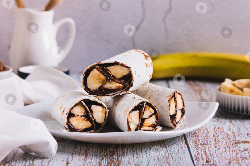 Скачать Сладкие булочки с шоколадом и бананом на тарелке на столе фотосток Ozero