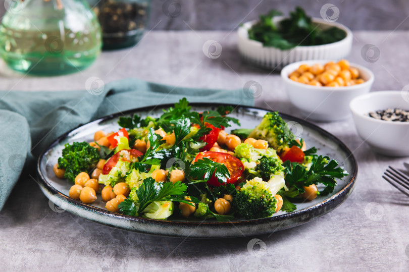 Скачать Вегетарианский салат с нутом, помидорами, брокколи и зеленью на тарелке на стол фотосток Ozero