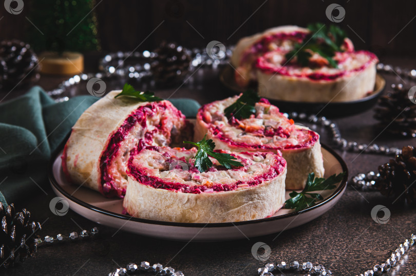 Скачать Традиционный салат "сельдь под шубой", завернутый в лаваш, на тарелке на столе фотосток Ozero