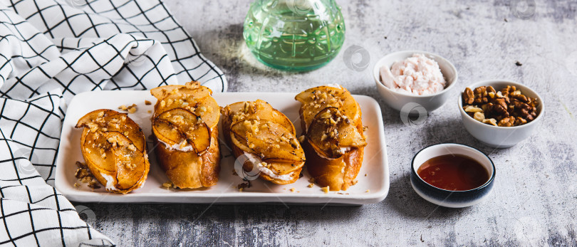 Скачать Сладкие бутерброды с рикоттой, печеной грушей, медом и орехами на тарелке на веб-баннере "Стол" фотосток Ozero