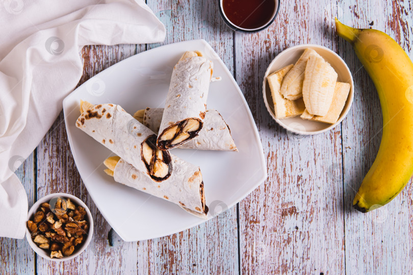 Скачать Сладкие булочки с шоколадом и бананом на тарелке на столе вид сверху фотосток Ozero