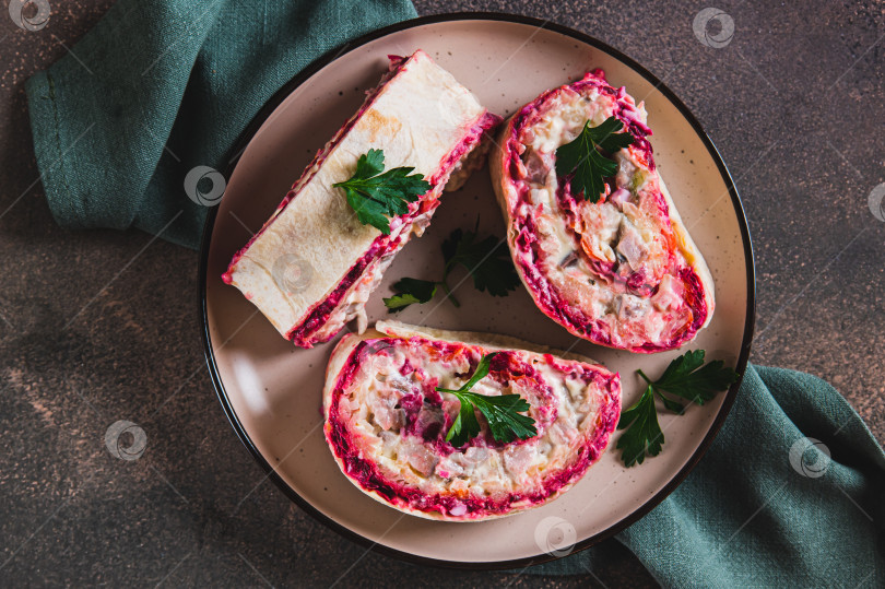 Скачать Традиционный салат "сельдь под шубой" крупным планом, завернутый в лаваш, на тарелке, вид сверху фотосток Ozero